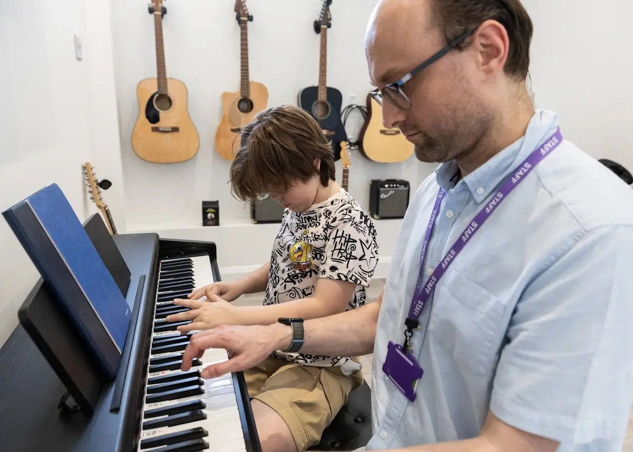A young person practising guitar with a tutor at YoungEducation